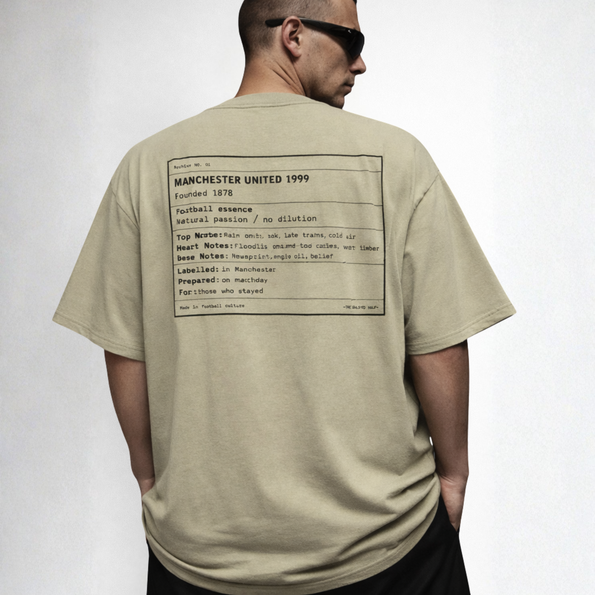 Man wearing a beige t-shirt with text on the back, standing against a plain background